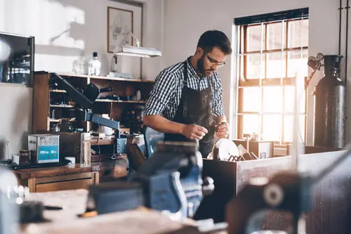 A metalworker at his bench among machines he has owned for years.