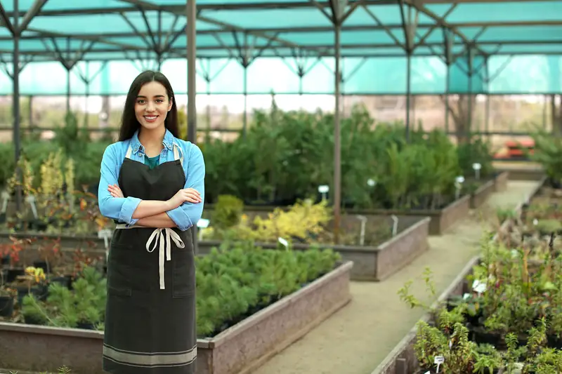 The owner of a plant nursery standing among the beds under its shade canopy.